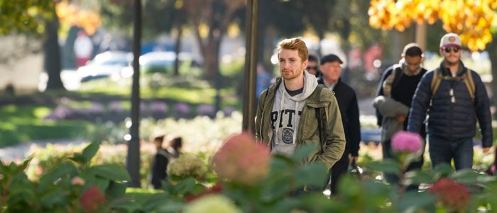 Student wearing Pitt sweatshirt walking on campus