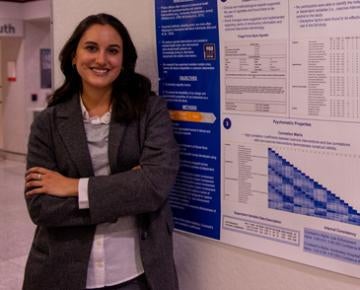 A social work student stands next to her research poster.